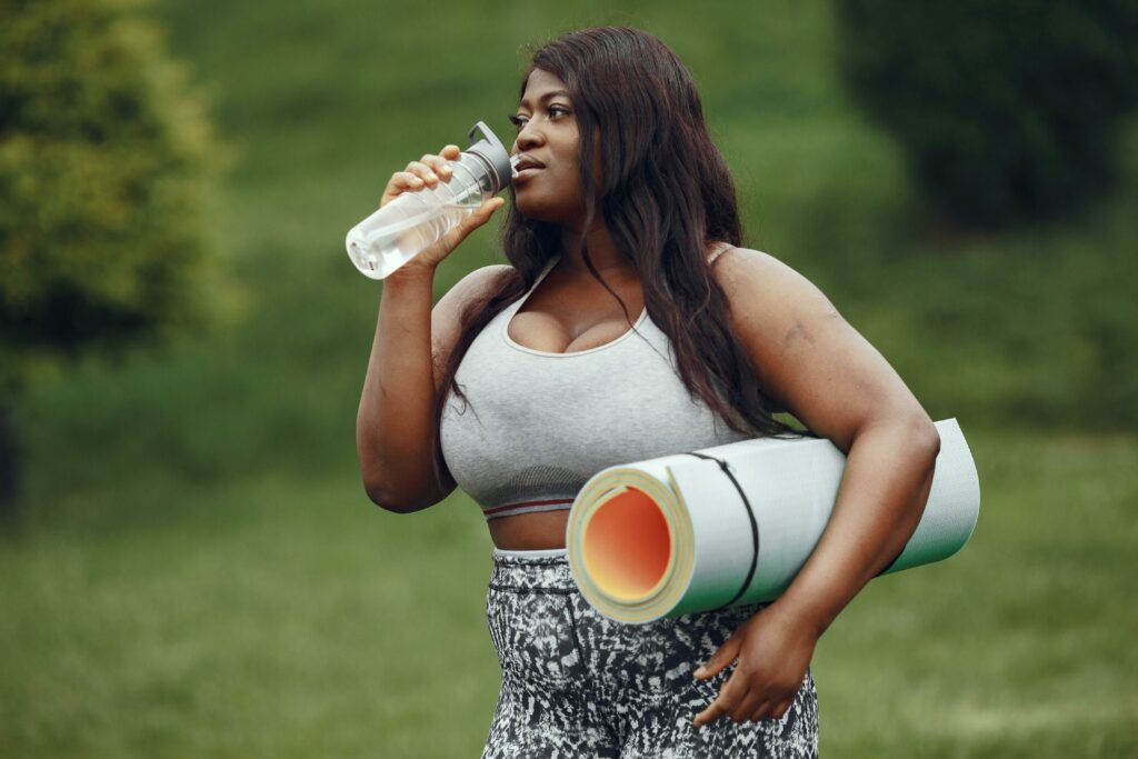 Woman Drinking Water with yoga Mat
